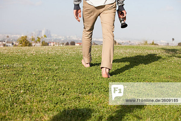 Man walking in field with video camera