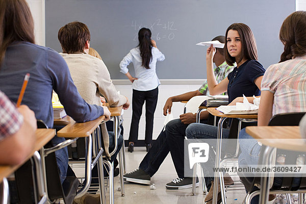 Schülerin mit Papierflugzeug im Klassenzimmer