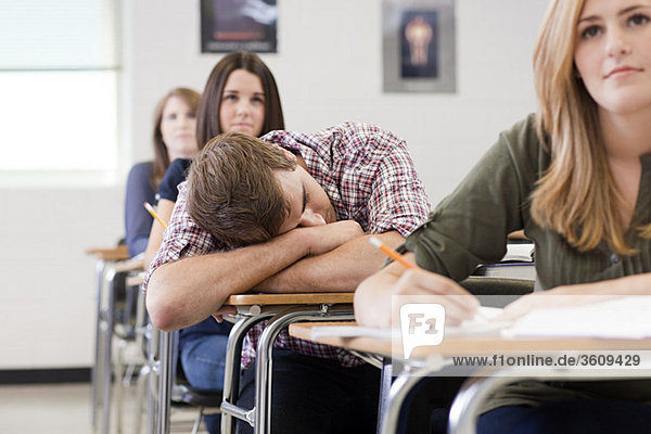Männlicher Gymnasiast schläft in der Klasse