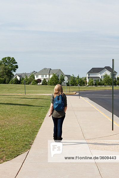 Female high school student walking along pavement