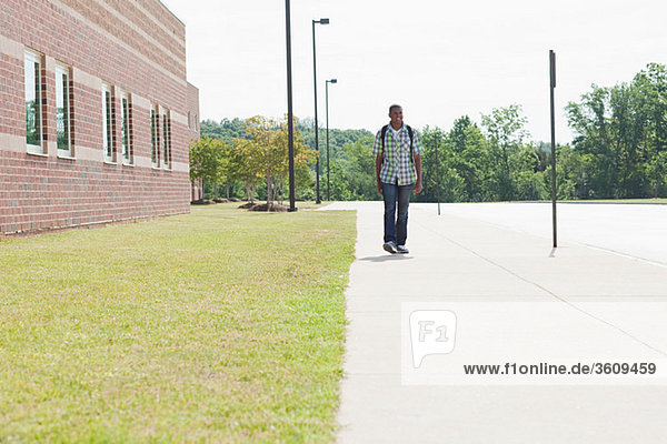 Male high school student walking by school