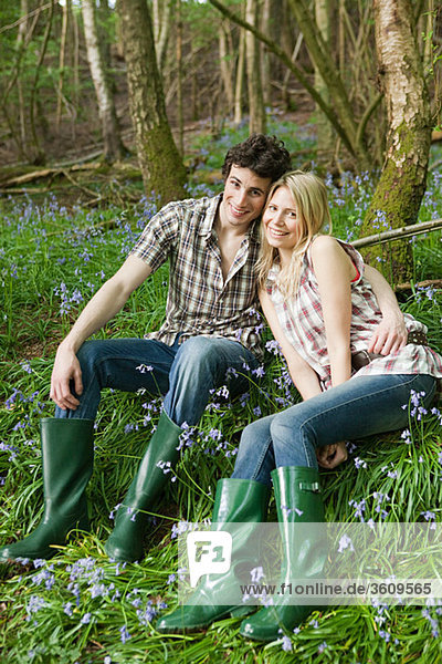 Young couple sitting amongst bluebells