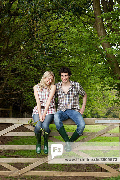 Young couple sitting on gate