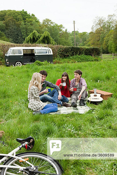 Friends sitting in field by camper van
