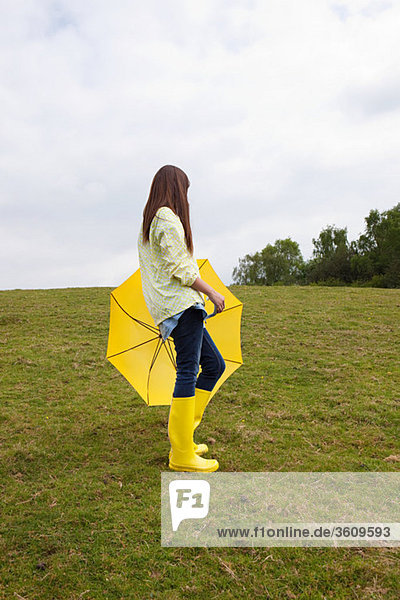Junge Frau im Feld mit Regenschirm