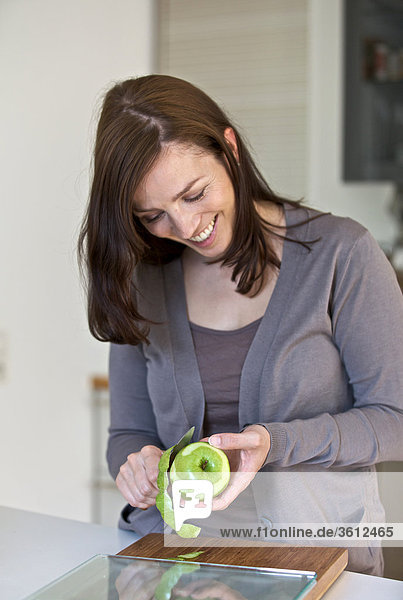 Woman peeling apple in kitchen