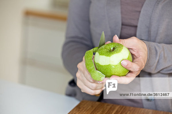 Woman peeling apple in kitchen  close-up