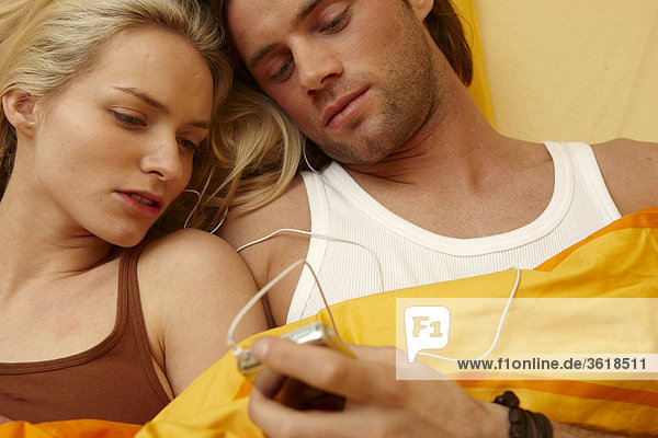 Junges Paar im Bett mit MP3-Player