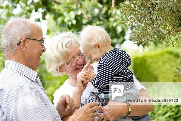 Großeltern mit Kleinkind im Garten