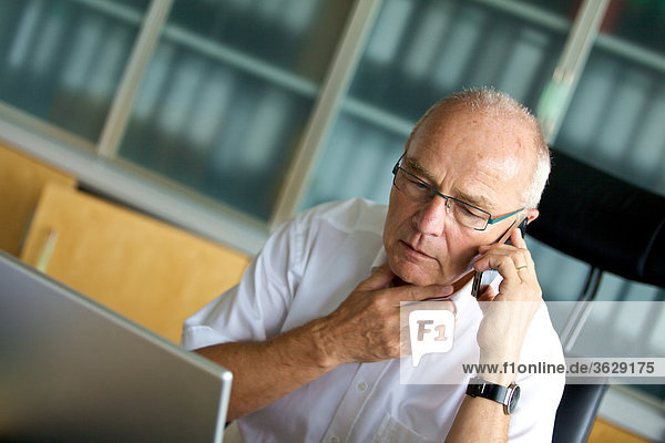 Senior man on cell phone in home office