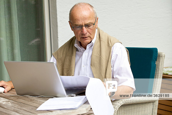 Senior benutzt Laptop auf der Terrasse