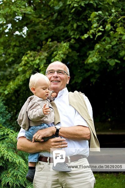 Grandfather carrying toddler outdoors