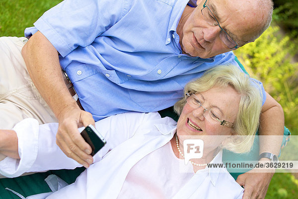 Glückliches Seniorenpaar mit Smartphone im Garten