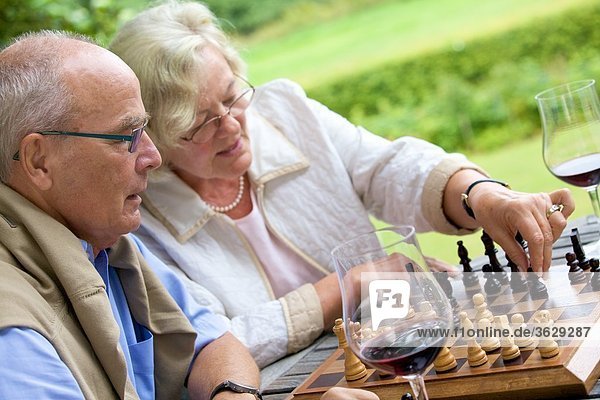 Seniorenpaar auf der Terrasse spielt Schach