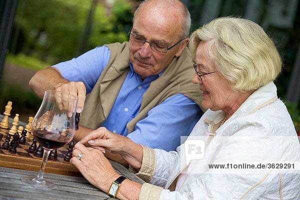 Seniorenpaar auf der Terrasse spielt Schach