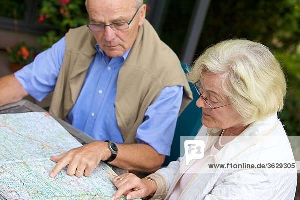 Seniorenpaar auf der Terrasse schaut auf Straßenkarte