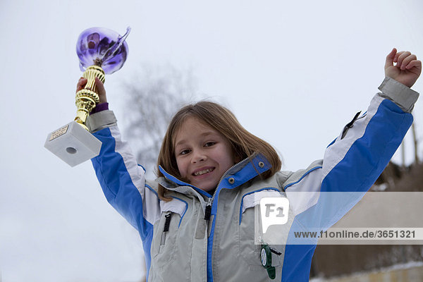 Mädchen  neun Jahre  freut sich über einen Pokal bei der Siegerehrung