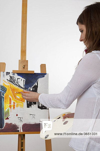 Junge Frau malt ein Bild mit Acrylfarben