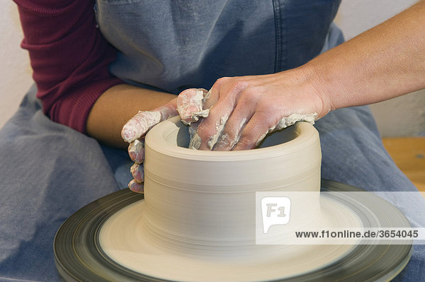Keramikerin arbeitet in ihrer Werkstatt auf der Töpferscheibe  Zylinder hochziehen  Geisenhausen  Bayern  Deutschland  Europa
