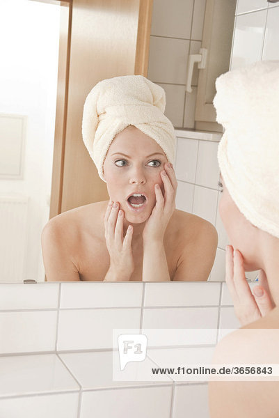 Junge Frau mit Handtuch auf dem Kopf vor dem Spiegel