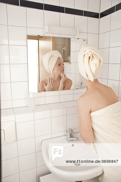 Frau im Bad vor dem Spiegel beim Begutachten ihres Gesichts
