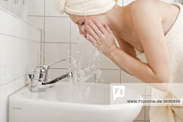 Frau wäscht Gesicht mit Wasser