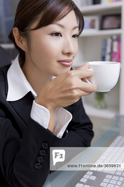 Geschäftsfrau beim Kaffeetrinken im Büro