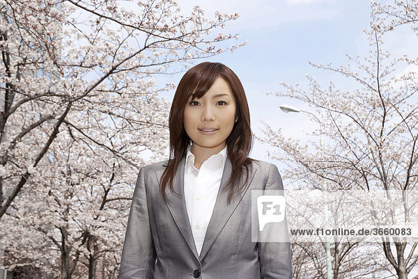 Businesswoman standing under cherry blossom tree
