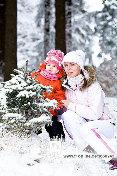 Kleines Mädchen und ihre Mutter im verschneiten Wald