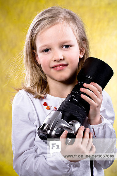 7-year-old girl holding digital camera with telephoto lens