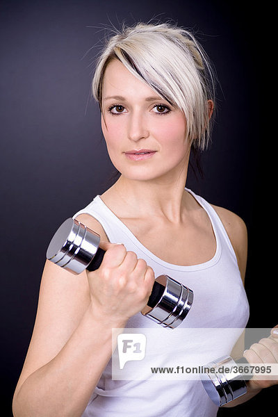 Young woman exercising with dumb bells