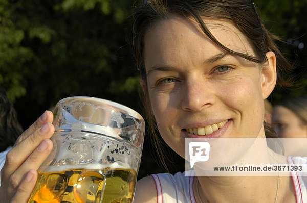 Portrait lächelnde junge Frau trinkt Maß Bier im Biergarten München Bayern