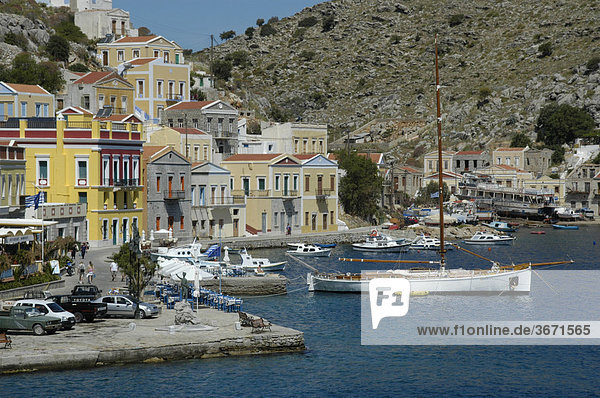 Blick auf die farbenfrohen ockerfarbenen Häuser mit Booten im Hafen der Insel Symi Griechenland