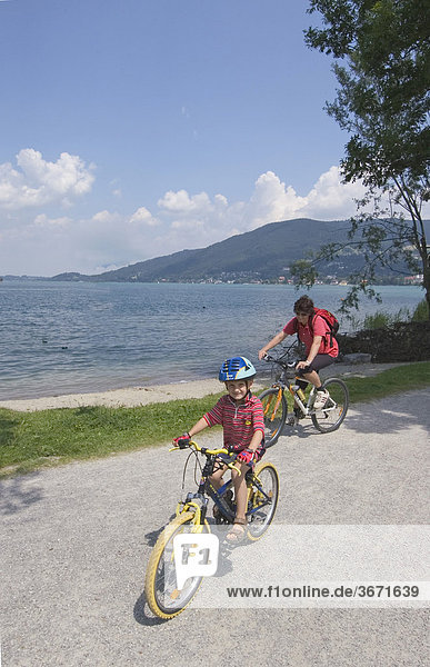 At the Tegernsee mother is cycling with her son on a bicycle tour