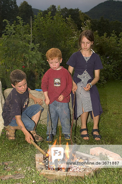 Children having a barbecue at an open fire place campfire game with fire