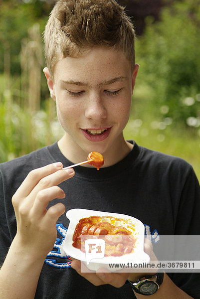 Junge isst currywurst