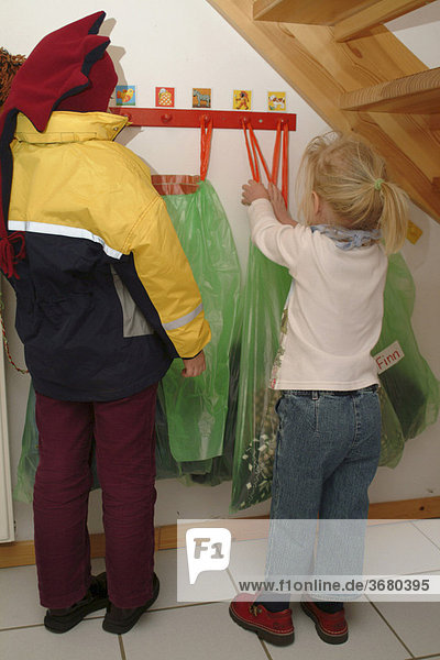 Kind im Kindergarten an Garderobe mit Müllsack fürKlamotten zum Schutz vor Läusen