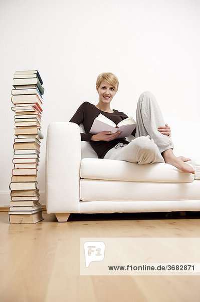 Frau beim Lesen eines Buches auf dem Sofa