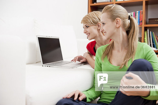 Women using laptop on sofa
