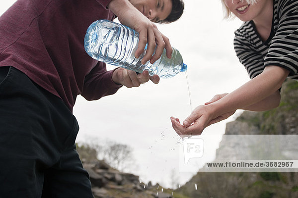 Mann gießt Wasser auf Frauenhände