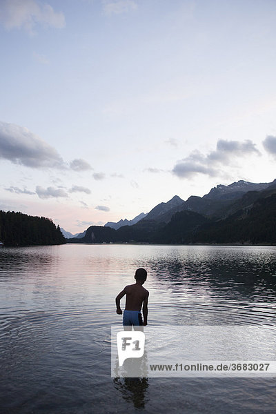 Young boy bathing in lake at night