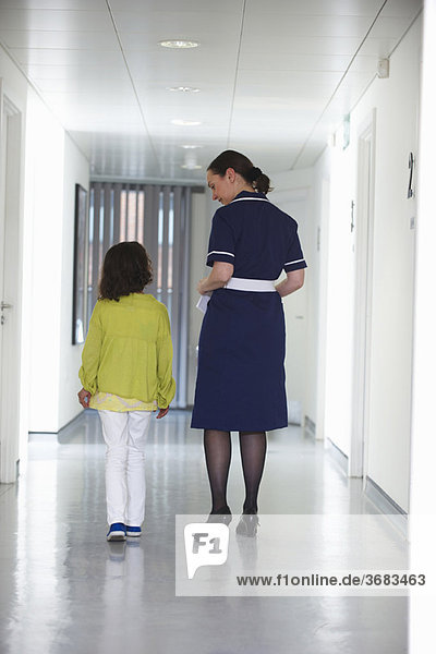 Nurse and young girl walking in corridor