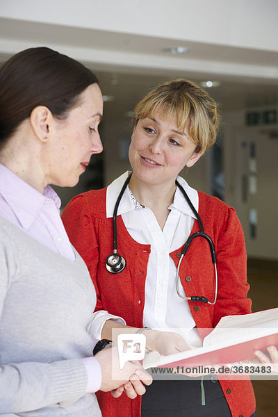 Female doctor with book talking to woman