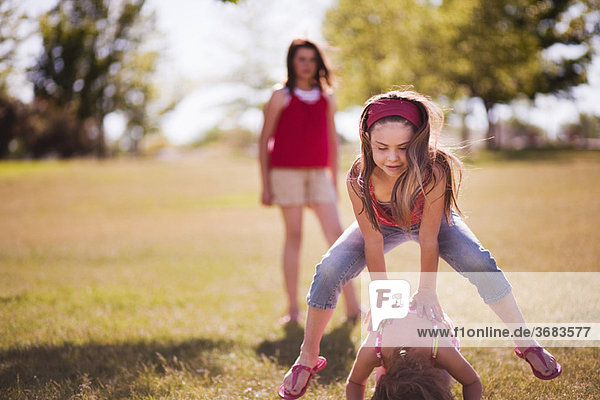 3 girls playing leap frog in park