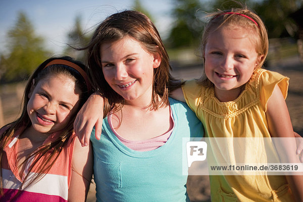 3 lächelnde junge Mädchen umarmend