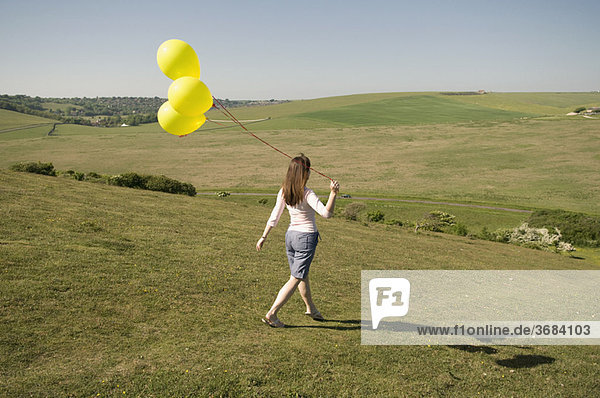 Frau mit Luftballons geht bergab