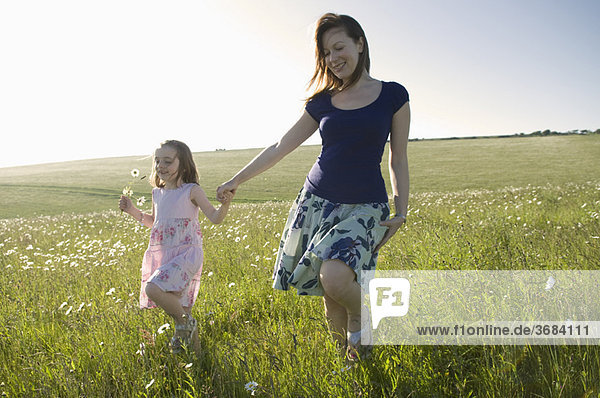 Woman and child walk thru sunny meadow