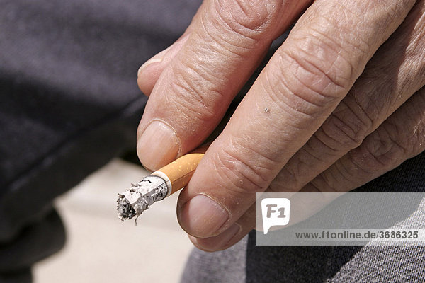 Abgebrannte Zigarette zwischen zwei Fingern