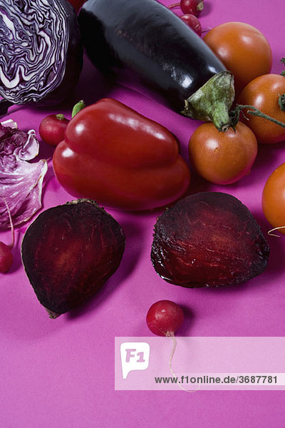 Anordnung von rotem und violettem Gemüse auf rosa Hintergrund