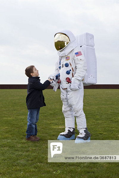 Ein Junge  der einem Astronauten die Hand schüttelt.